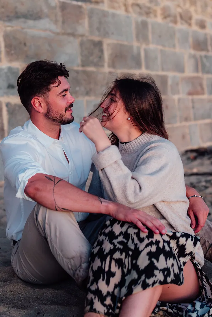 Couple complice assis contre un mur de pierre